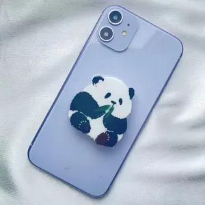 Close-up of a cute panda acrylic phone grip stand attached to a purple smartphone.