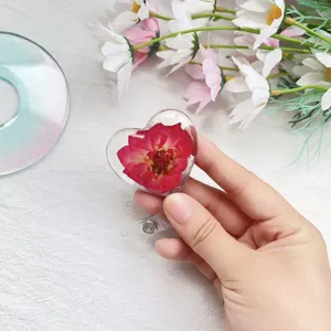 Nahaufnahme eines herzförmigen Ausweishalters mit einer echten roten Trockenblume