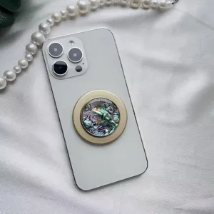 Dettaglio di un supporto per telefono magnetico con motivo a conchiglia e bordo dorato.