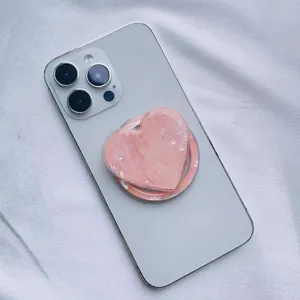 Close-up of a pink shell heart phone grip attached to a smartphone with MagSafe design.