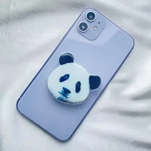 Detail view of a cute panda face acrylic expandable phone grip on a purple phone