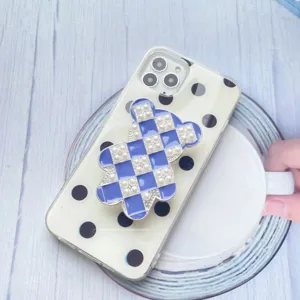 Primo piano di un supporto per telefono a forma di orso a scacchi blu con perle