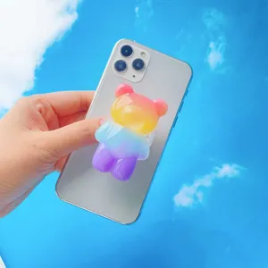 Detailaufnahme eines süßen regenbogenfarbenen Bären-Handyhalters auf einem Smartphone