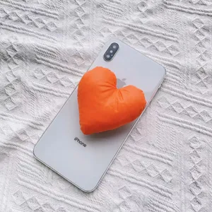 Nahaufnahme des orangefarbenen, gepolsterten Herz-Handyhalters an einem Smartphone