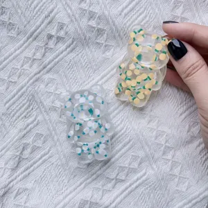 Close-up of cute bear-shaped acrylic phone grips with floral and fruit patterns.