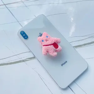 Vue détaillée d'un support de téléphone mignon en peluche rose sur un smartphone blanc