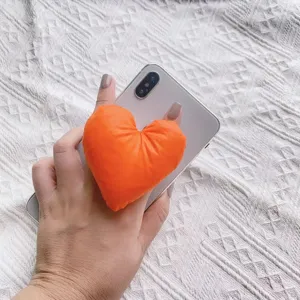 Nahaufnahme eines leuchtend orangefarbenen herzförmigen Handy-Halters aus Stoff