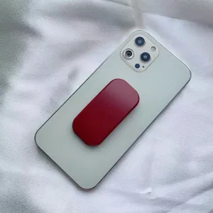 Supporto per telefono a spinta rosso attaccato al retro di uno smartphone grigio.