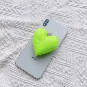 Neongrüner herzförmiger gepolsterter Stoff-Handygriff an einem weißen Smartphone
