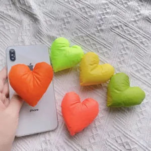 Detailansicht farbenfroher herzförmiger Stoff-Handyhalterungen auf einem weißen iPhone