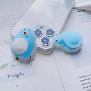 Close-up of cute light blue penguin and turtle squishy toys on clear phone grips