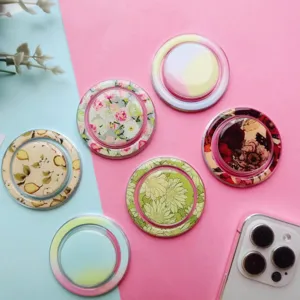 Assorted floral and gradient magnetic phone grips displayed on a pink and blue background