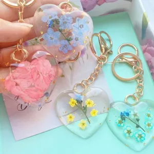 Detail of heart-shaped resin keychains with colorful real dried flowers and gold rings