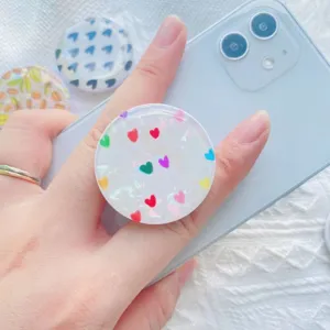 Close-up van een telefoonhouder met schelpenpatroon en gekleurde hartjes op de smartphone