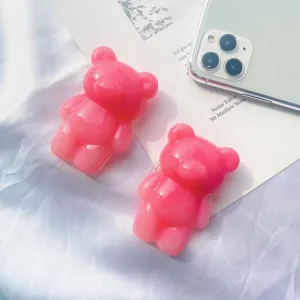 Soportes plegables para teléfono con forma de oso rosa degradado sobre fondo de tela blanca