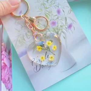 Close-up of heart-shaped resin keychain with real dried flowers and gold foil