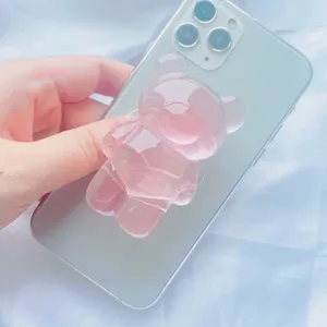 Gros plan d'un support de téléphone en forme d'ours rose translucide sur un smartphone