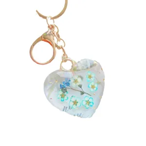 Heart-shaped clear resin keychain featuring real blue dried flowers and gold lobster clasp