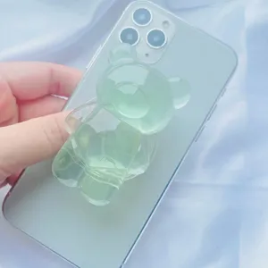 Détail d'un support de téléphone en forme d'ours vert translucide sur un smartphone