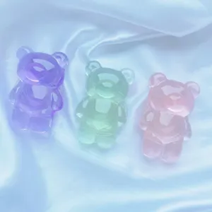 Vue détaillée de trois supports de téléphone ours en gomme translucides sur tissu soie