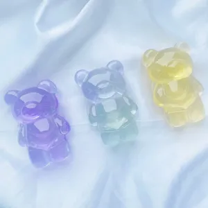 Détail de trois supports de téléphone en forme d'ours translucides sur du satin
