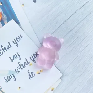 Detailed view of semi-transparent matte pink bear-shaped phone grip on a decorative card.