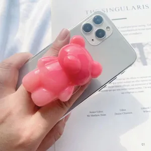Primer plano de un soporte para teléfono con forma de oso 3D rosa en un smartphone plateado