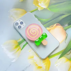 Detailopname van een roze lolly-telefoongreep van hars met een groene strik op de mobiel
