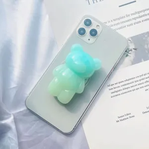 Primer plano detallado de un soporte para móvil con forma de oso verde degradado en smartphone