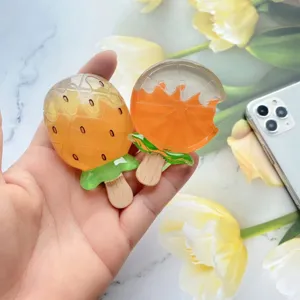 Detailweergave van hars telefoonhouders in de vorm van fruitijsjes met aardbei en sinaasappel