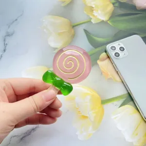 Close-up van een schattige roze lolly-vormige hars telefoonhouder, in de hand gehouden