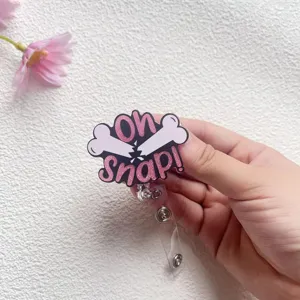Dettaglio di un divertente porta badge a forma di osso Oh Snap con glitter rosa