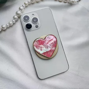 Dettaglio del supporto per telefono a cuore con trama a conchiglia e bordo oro