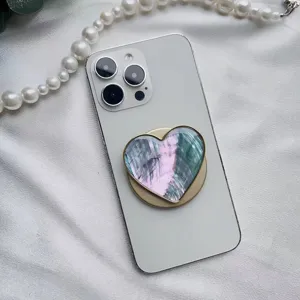 Macro del supporto per telefono a cuore con motivo a conchiglia iridescente e bordo dorato
