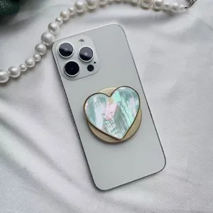 Dettaglio di un supporto magnetico per telefono a forma di cuore con trama in madreperla.