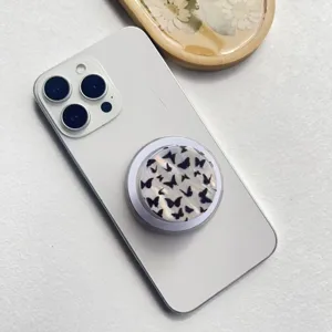 Makro-Detail eines schillernden Schmetterlings-MagSafe-Handyhalters an einem weißen Smartphone