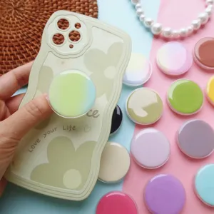 Diverse ronde telefoonhouders in macaronkleuren op een gebloemd telefoonhoesje