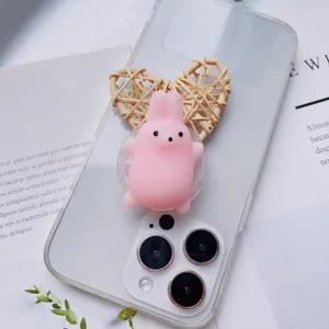 Close-up of pink squishy rabbit phone grip on a clear phone case with heart prop.