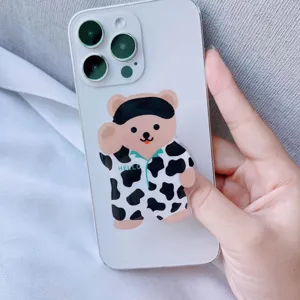 Nahaufnahme eines süßen Handy-Griffs aus Acryl in Bärenform an einem weißen Smartphone.