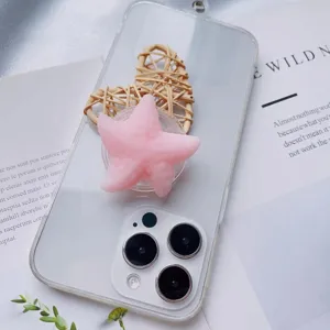 Close-up of pink starfish squishy phone grip on transparent case with straw heart prop.