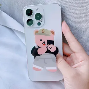 Detail eines süßen rosa Cartoon-Bären-Acryl-Handygriffs an einem weißen Smartphone