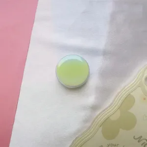 Close-up van een ronde macaron groene gradiënt telefoonhouder op witte zachte stof