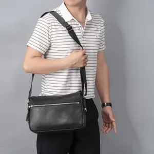 Men black leather shoulder bag worn detail view, premium casual messenger bag with zip pocket.