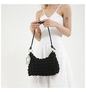 Close-up of black pleated bubble texture bag with floral charm and knotted strap