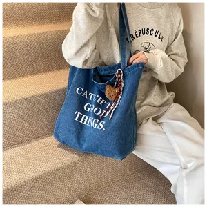 Detailed view of large capacity denim tote bag with chic print and cute pendant charm.