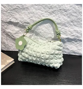 Close-up of mint green ruched shoulder bag with flower charm and knotted strap