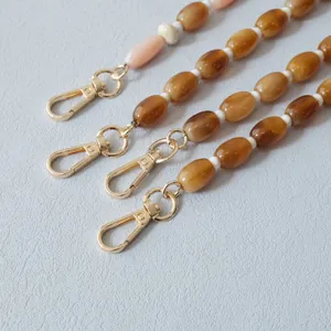Gros plan de lanières en perles acryliques caramel avec fermoirs mousquetons dorés
