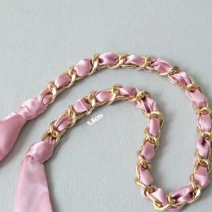 Détail de la chaîne dorée de 1,5 cm entrelacée d'un foulard en soie rose pour sacs