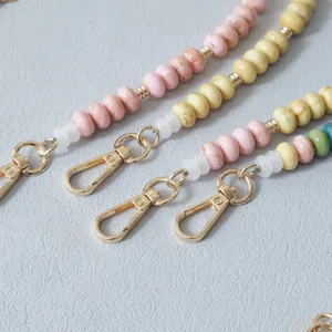 Close-up of colorful acrylic bead straps with gold lobster clasps for phone and bags.