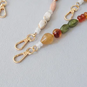 Vue détaillée d'une sangle en perles de résine acrylique avec fermoirs mousqueton dorés
